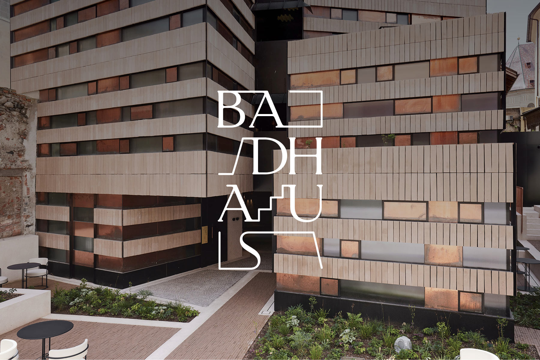 Moderne Fassade eines Gebäudes mit geometrischem Design und Pflanzen.