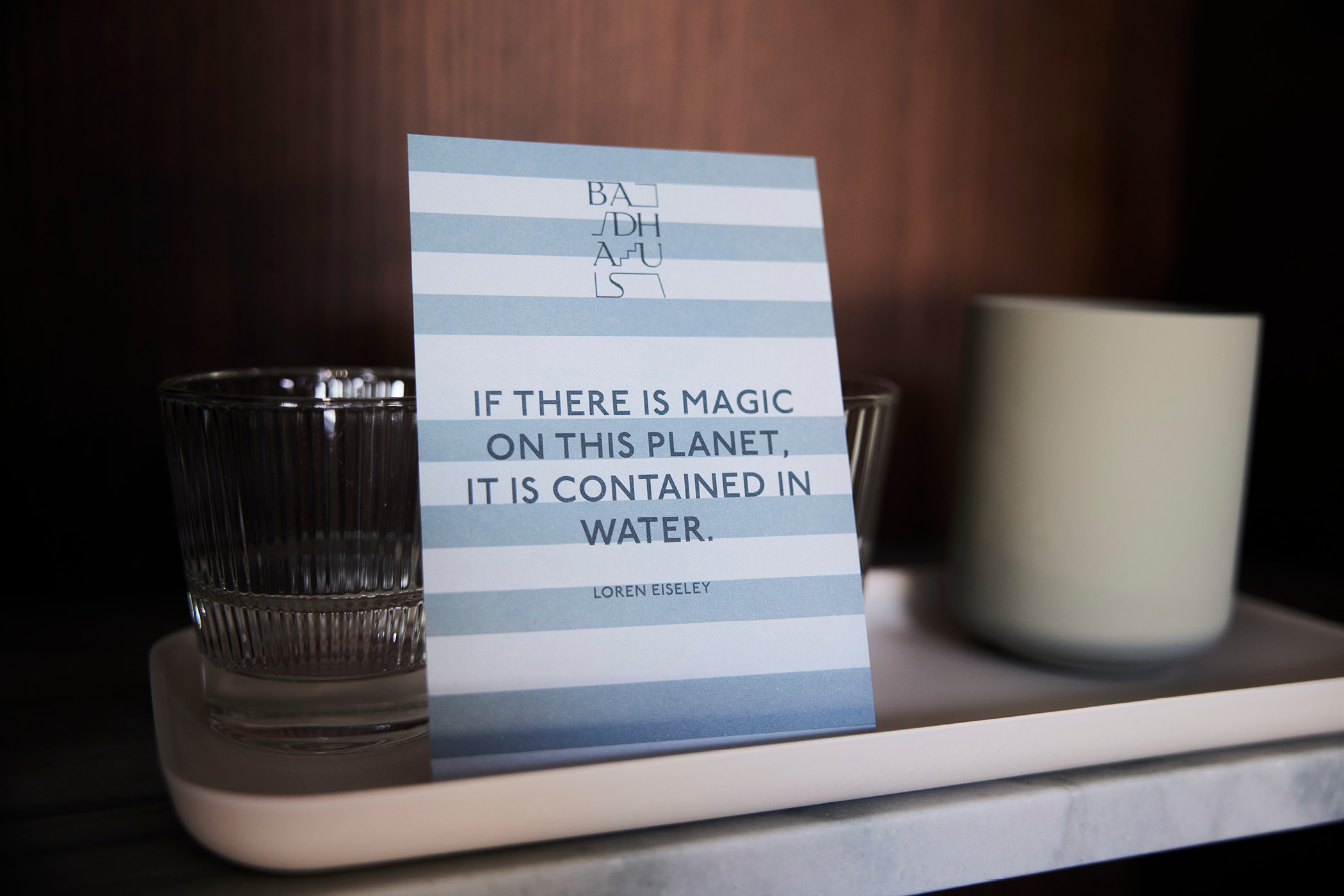 Zitatkarte mit Text über Magie und Wasser, mit Glas und Kerze auf Tablett