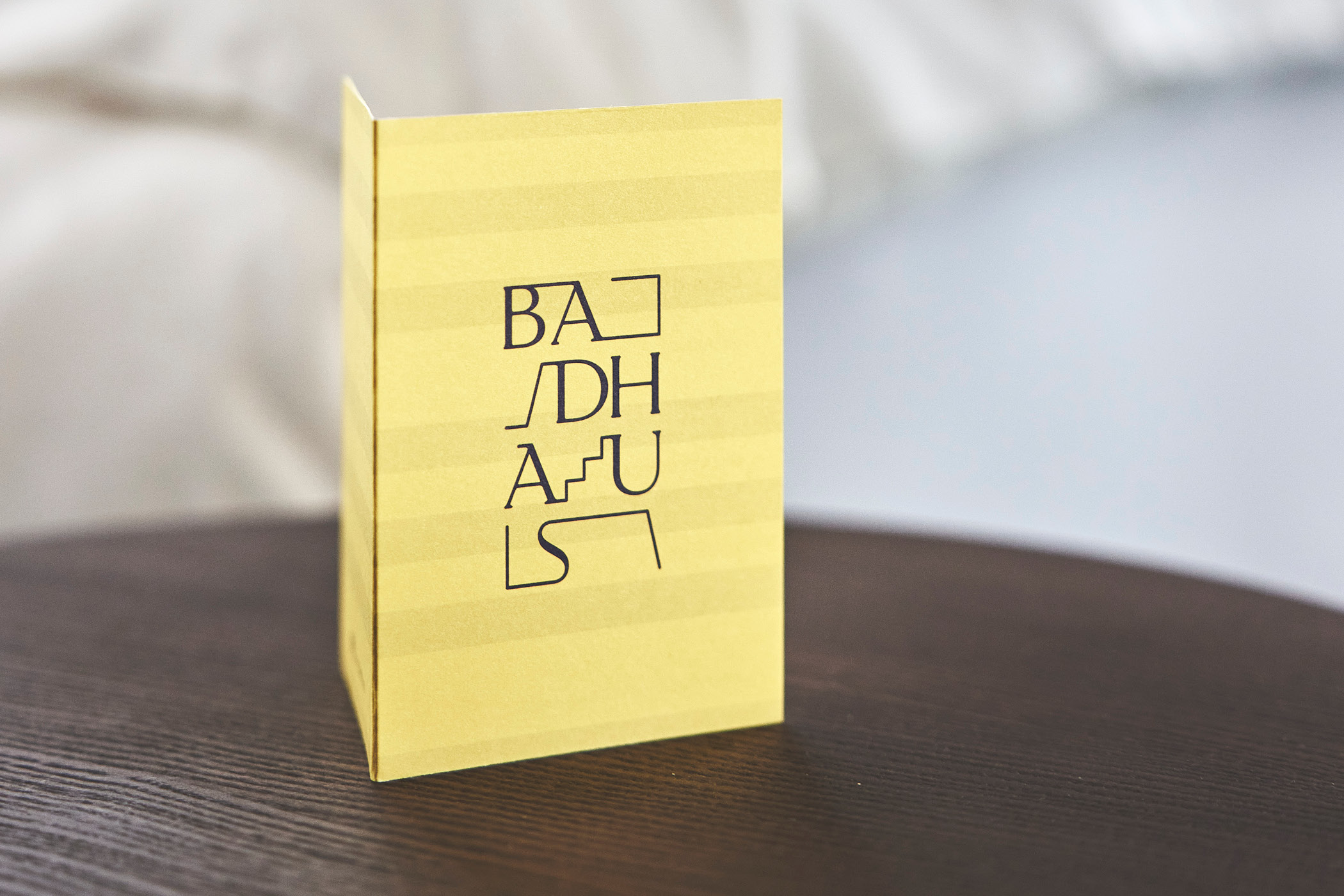 Gelbe Karte mit schwarzem Schriftzug 'BADHAUS' auf Holztisch