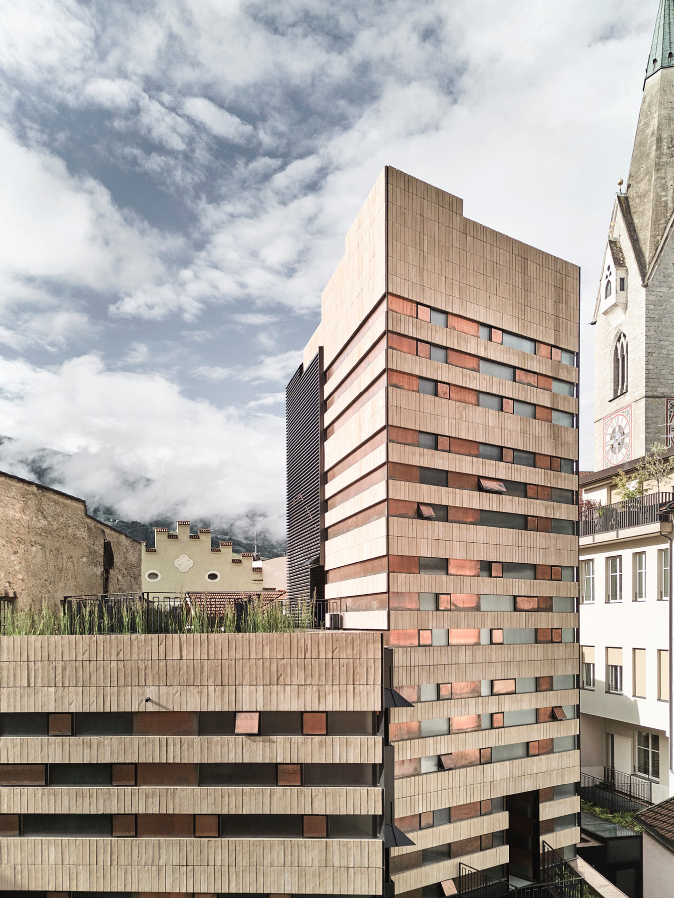 Moderne Architektur neben historischer Kirche unter bewölktem Himmel