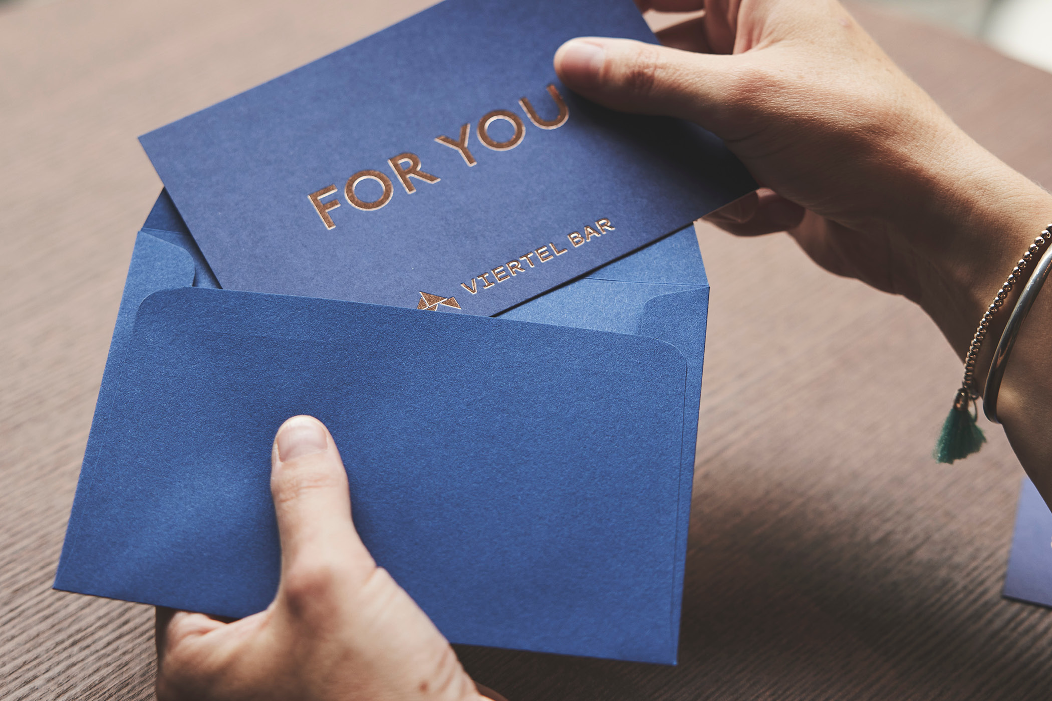 Hand hält blaue Karte mit Aufschrift 'FOR YOU' in blauer Hülle