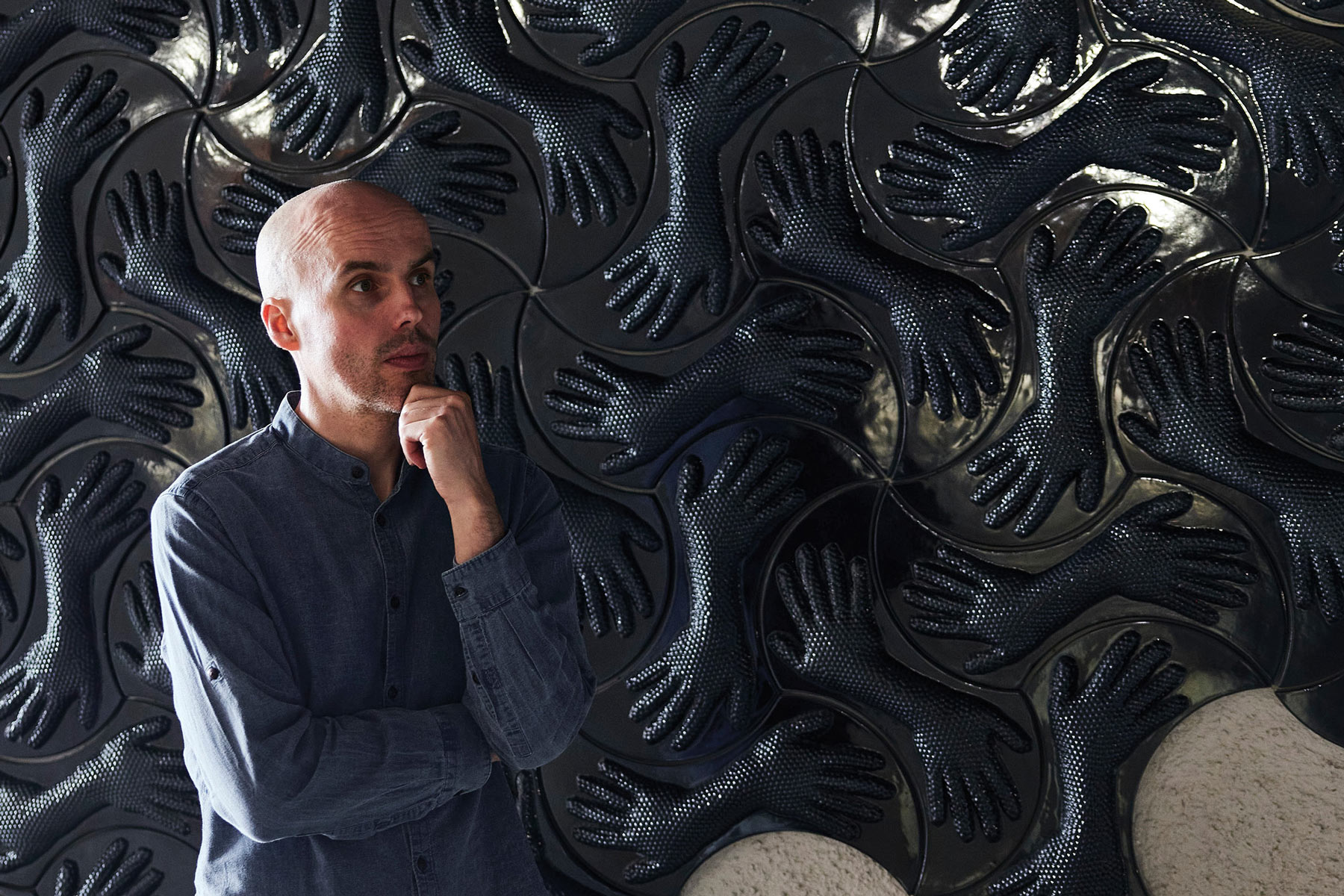 Mann vor Kunstwerk mit schwarzen, texturierten Handmotiven