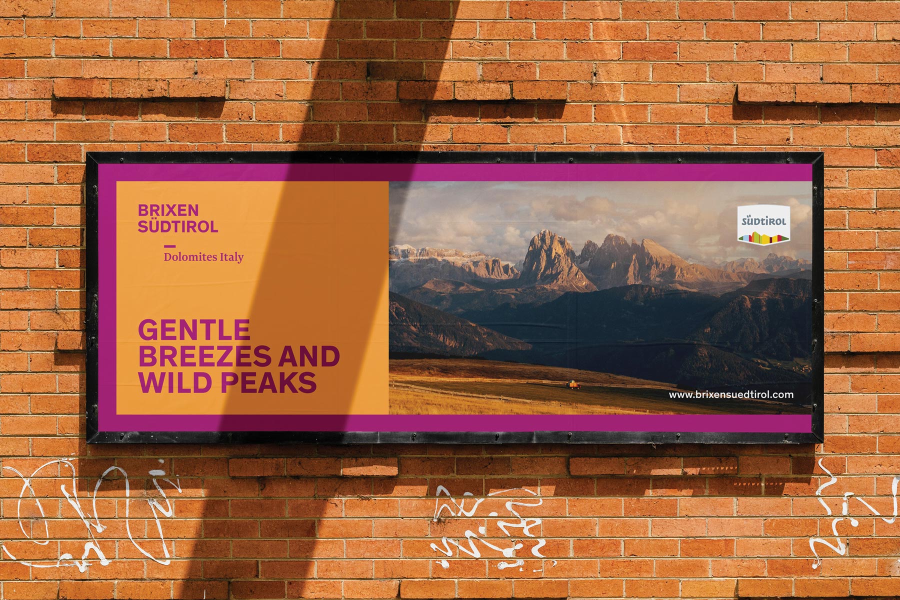 Werbeplakat für Brixen Südtirol mit Dolomitenpanorama auf Ziegelwand.