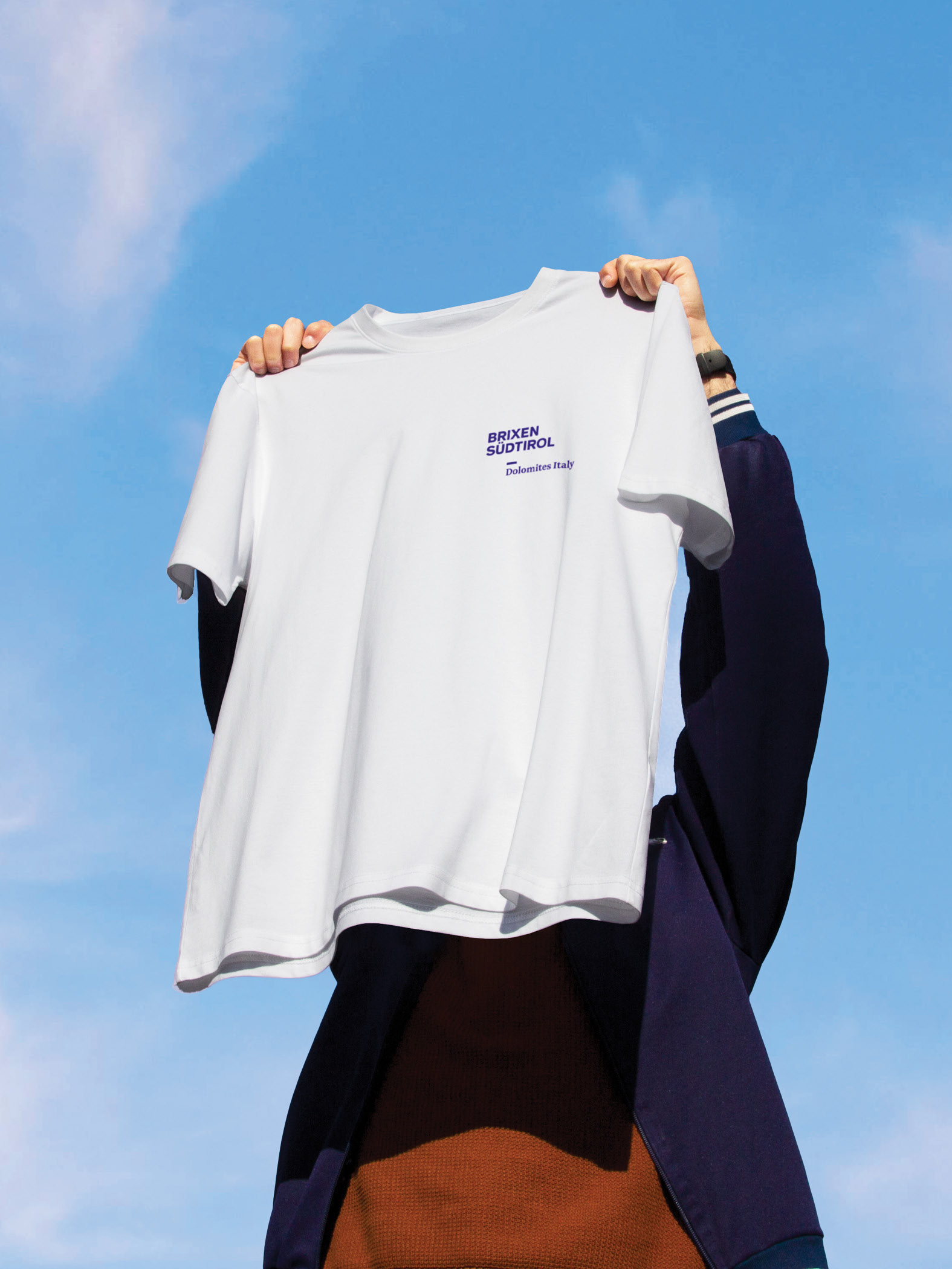 Person hält weißes T-Shirt mit Aufschrift 'BRIXEN SÜDTIROL' in die Luft