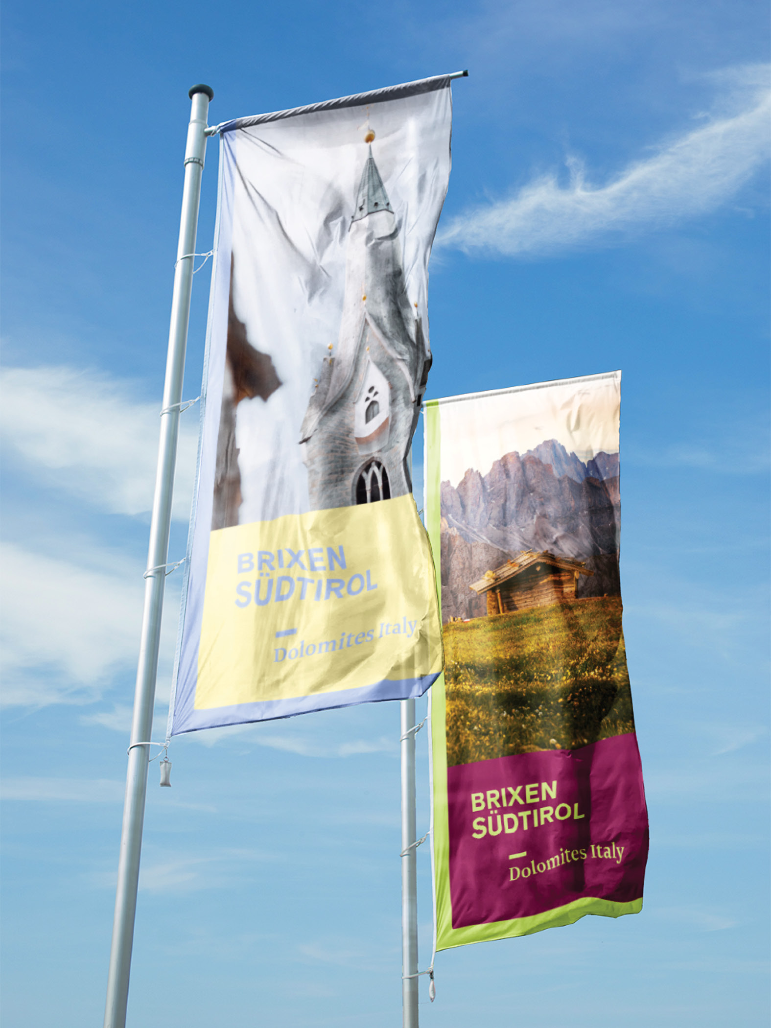 Zwei Brixen Südtirol Fahnen vor blauem Himmel, Dolomitenmotiv.