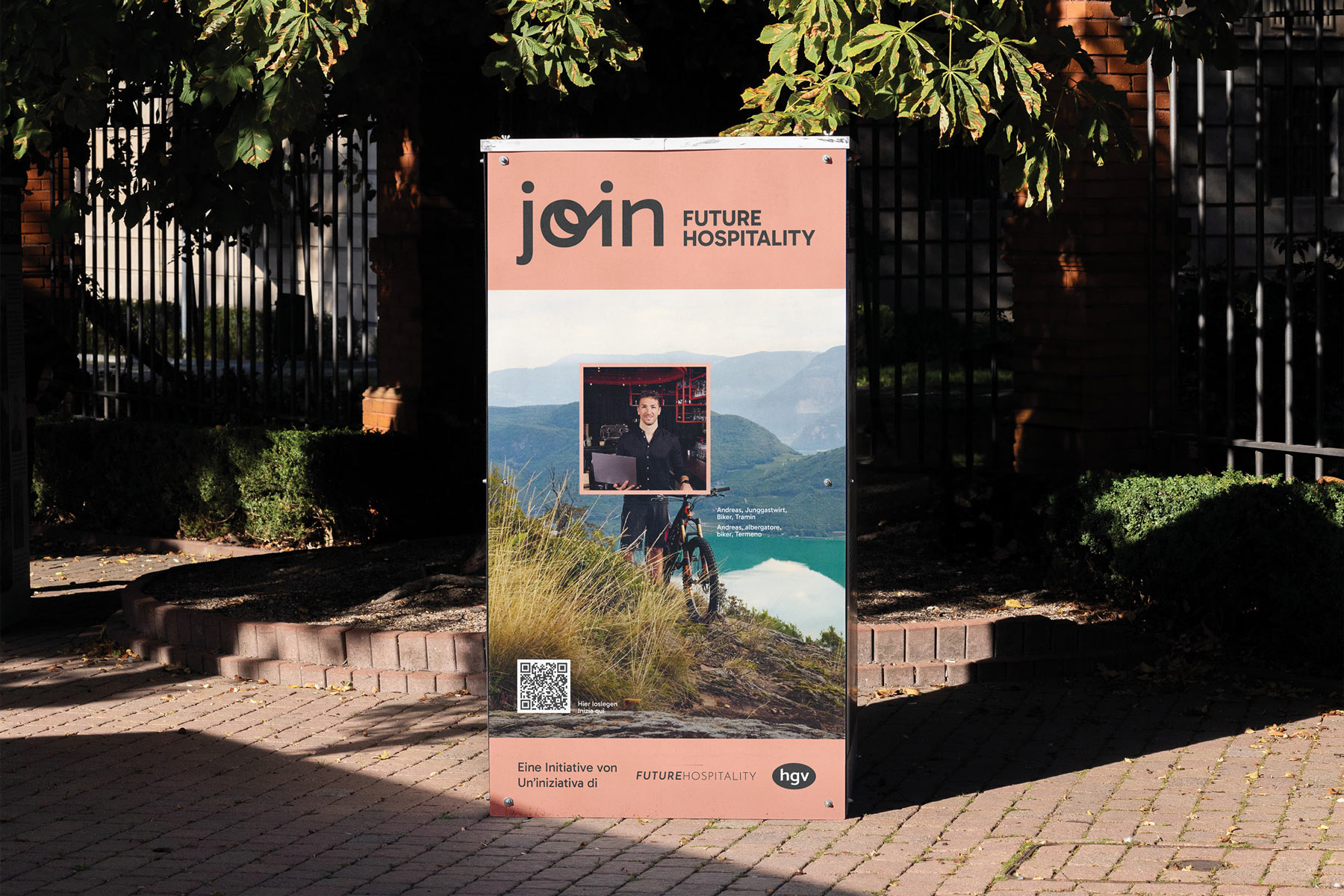 Plakat mit 'Join Future Hospitality' vor Bäumen und Backsteinmauer