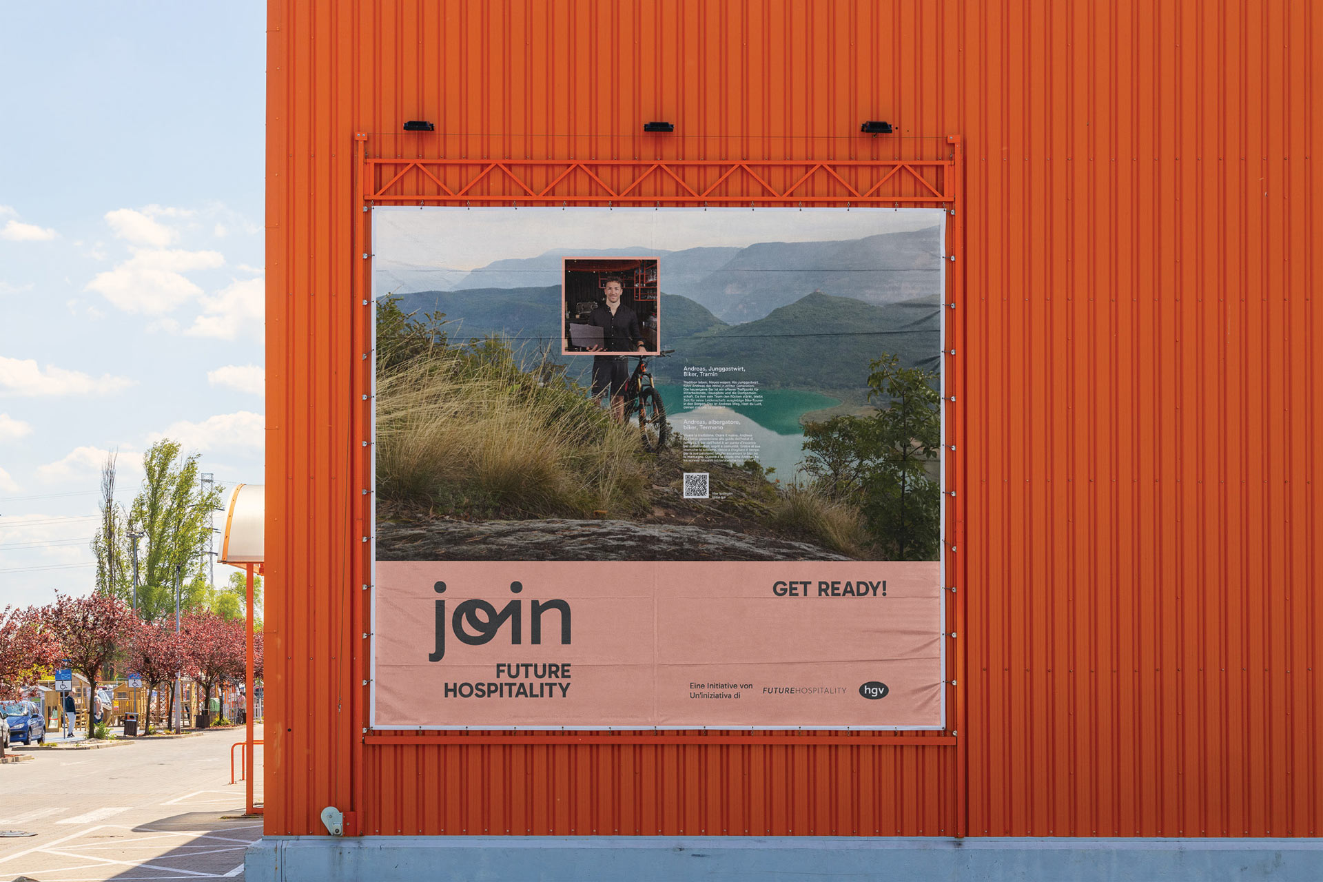 Plakat mit Landschafts- und Porträtfoto an orangefarbener Gebäudewand, Text: 'Join Future Hospitality'.