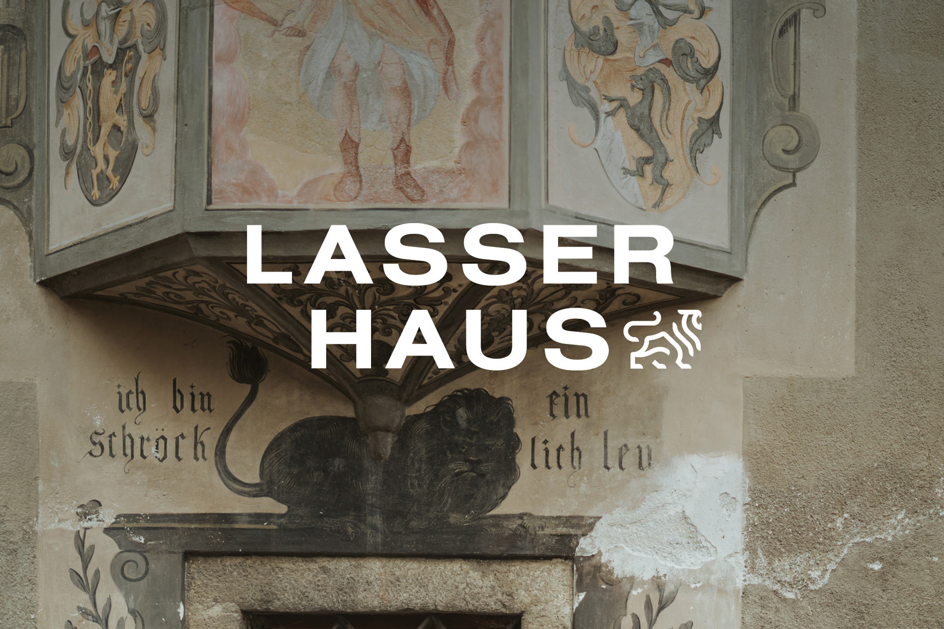 Fassade mit Wandmalerei und dem Text 'Lasser Haus' in großen Buchstaben.