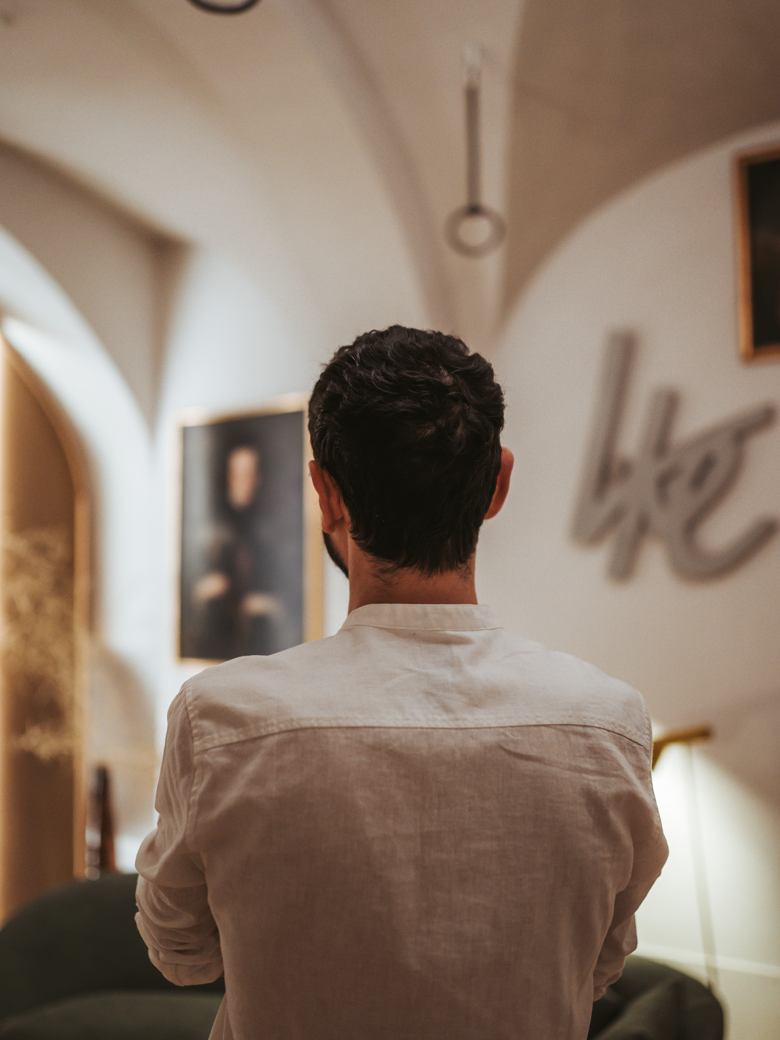 Person in heller Galerie mit Gewölbedecke und Gemälden