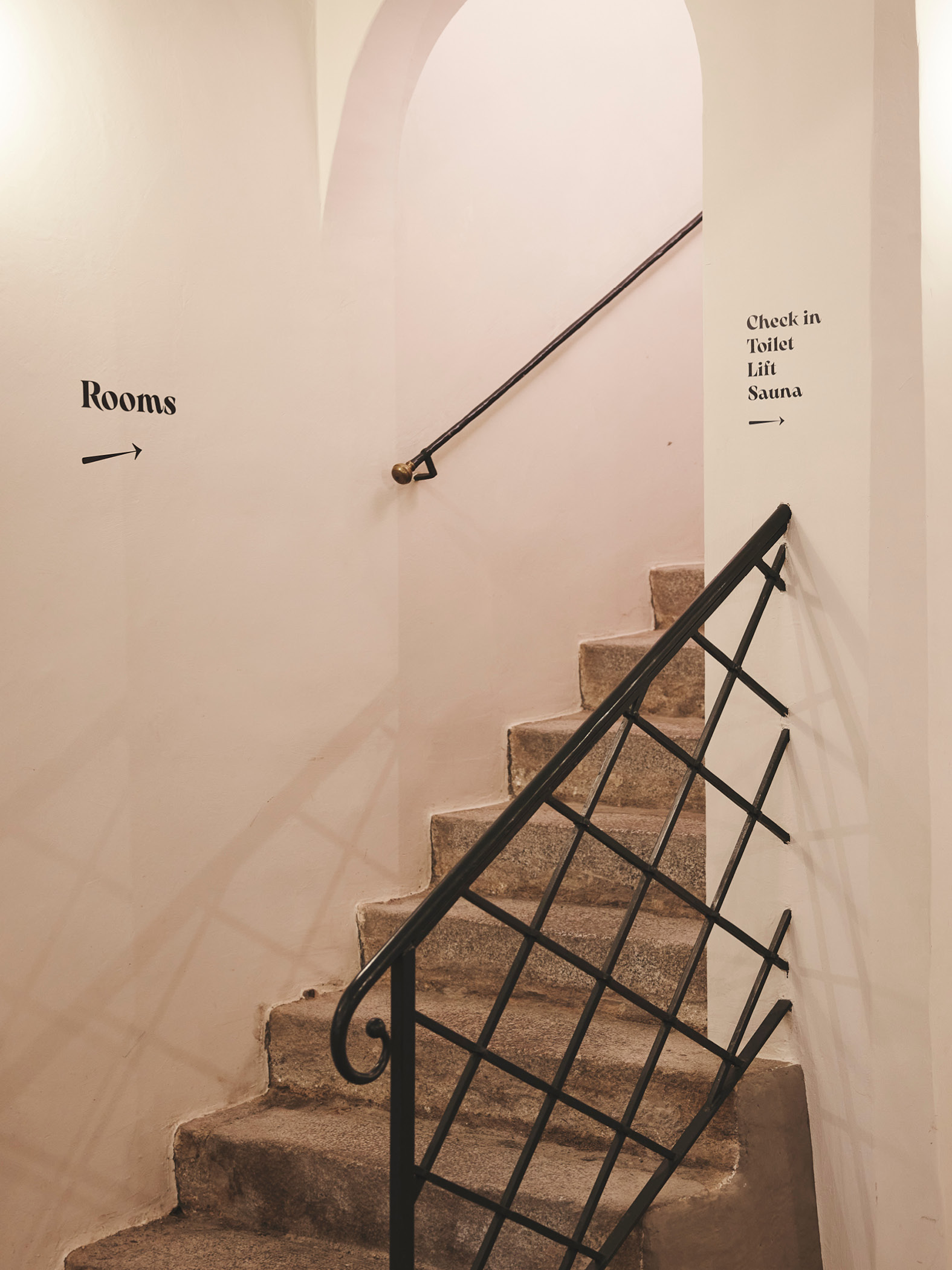 Steinwendeltreppe mit Schildern zu Zimmern und Einrichtungen