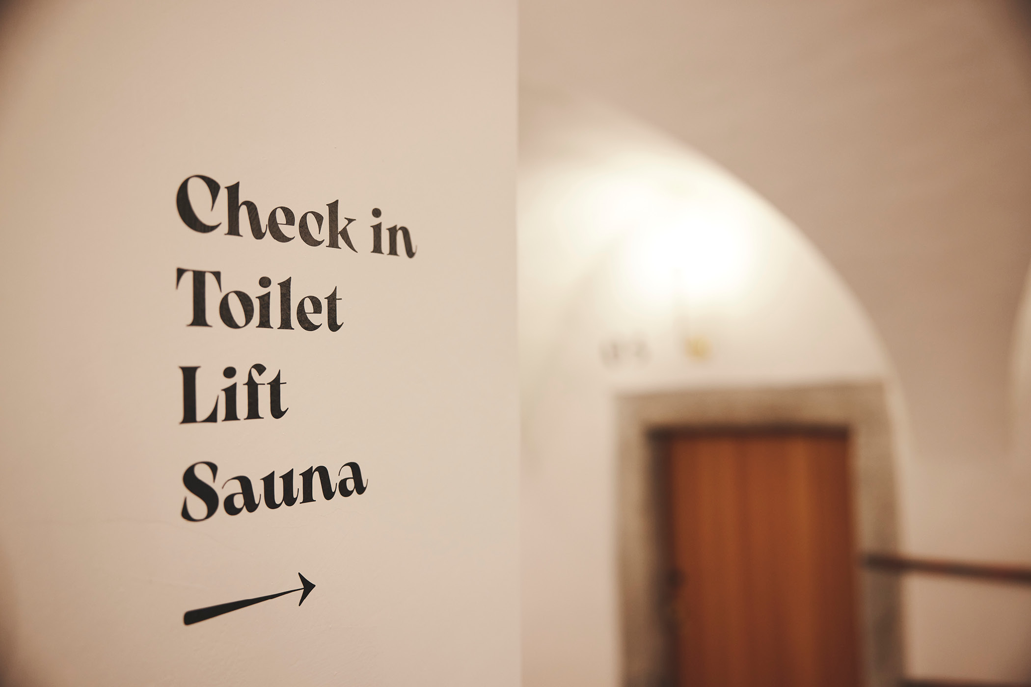 Richtungsschilder in einem Gebäude: Check in, Toilet, Lift, Sauna.