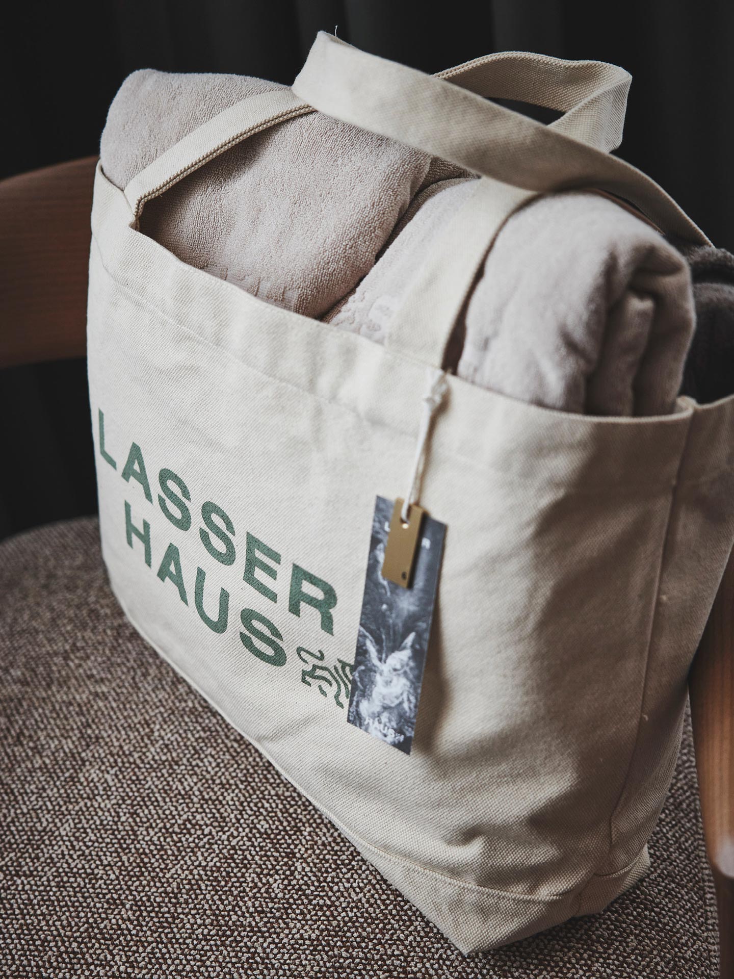 Stofftasche mit Handtüchern und Lasserhaus-Schriftzug auf Stuhl