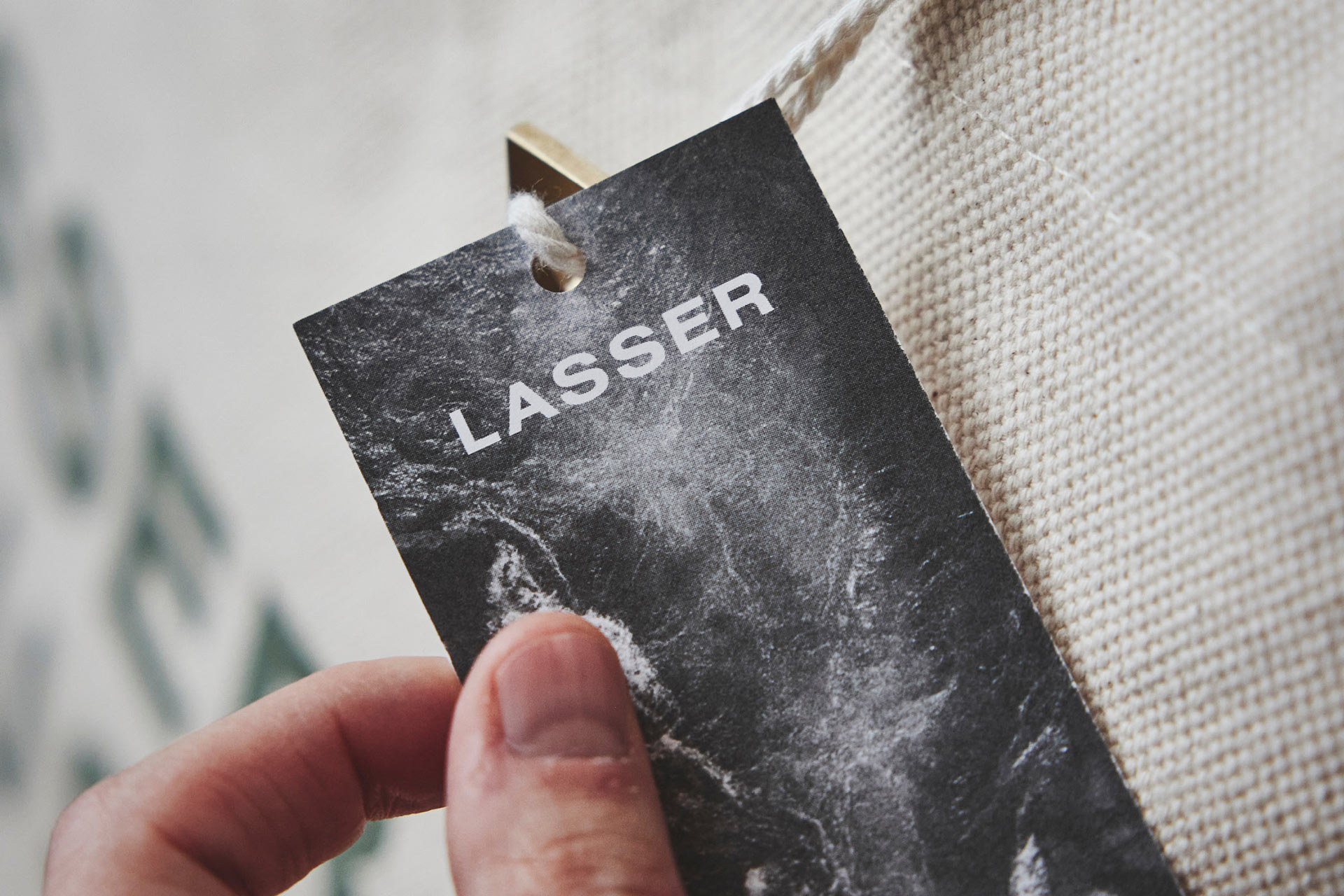Hand hält Etikett mit Aufschrift 'LASSER' an Stofftasche
