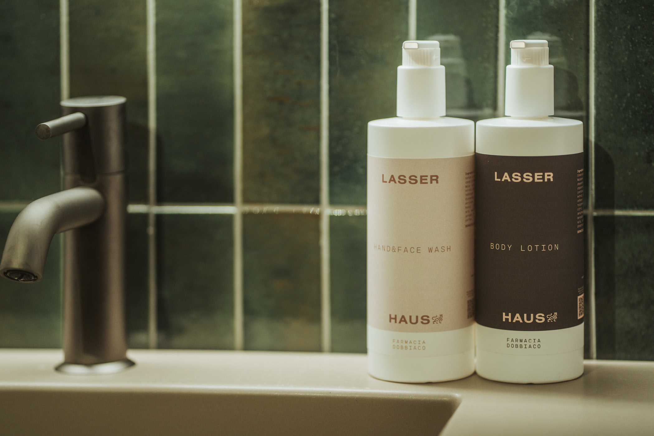 Zwei Pflegeprodukte von Lasser auf einer Badezimmertheke neben einem Wasserhahn