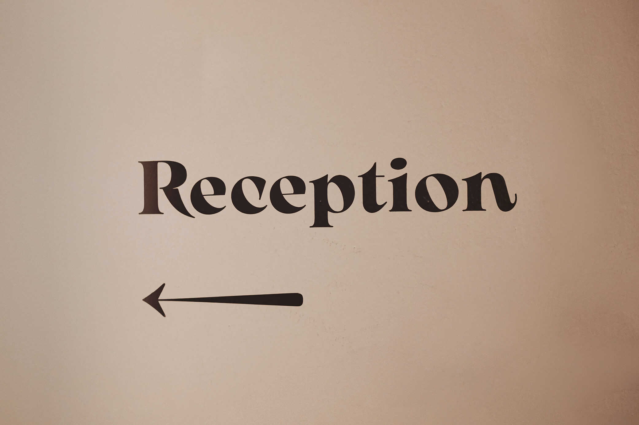 Wandschild mit 'Reception' und linksweisendem Pfeil