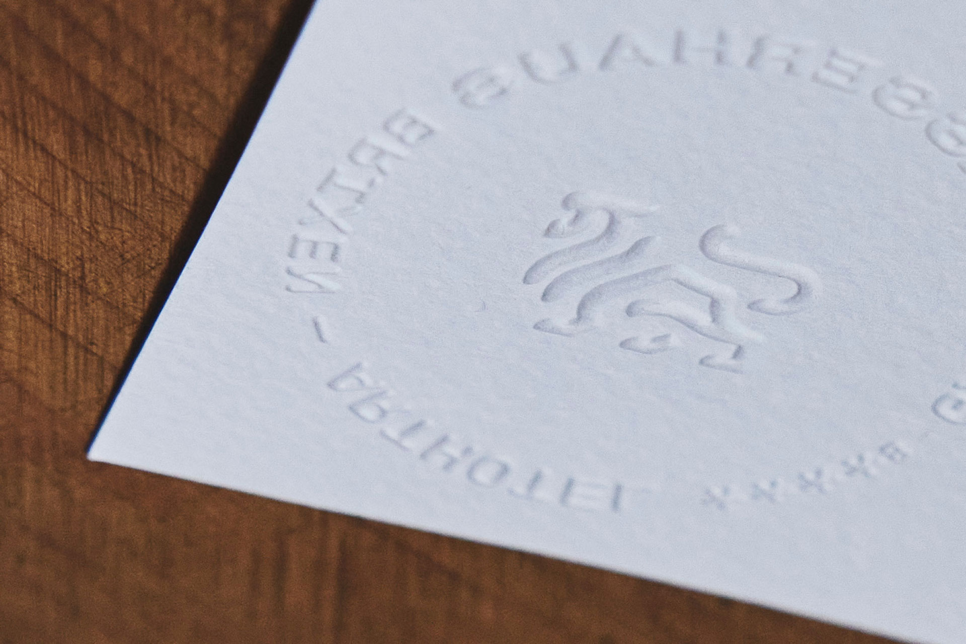 Geprägtes Logo und Text auf weißem Papier vor Holzuntergrund
