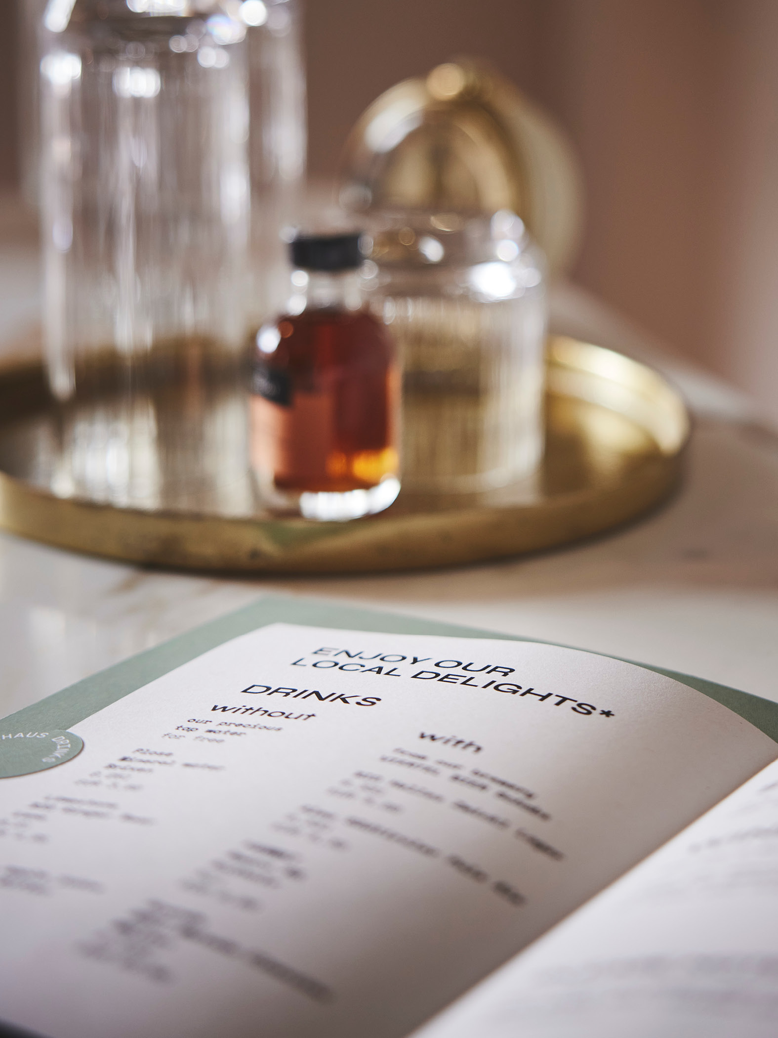 Offene Getränkekarte auf einem Tisch, daneben Glasflasche auf Tablett