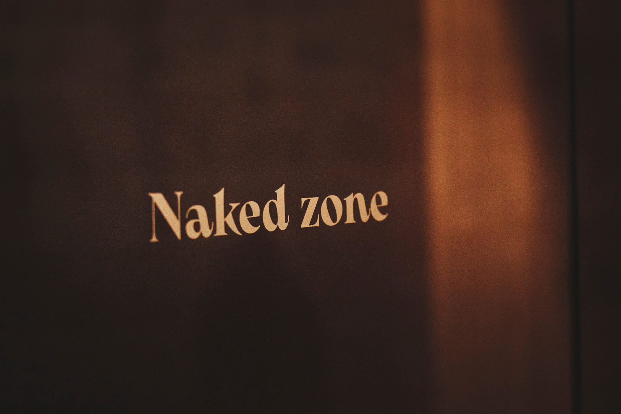 Duscheingang mit Schild 'Naked zone', warme Beleuchtung im Art