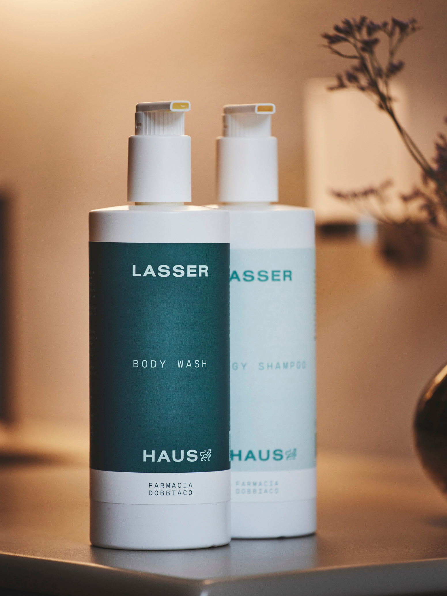 Zwei Pflegeprodukte von Lasserhaus auf einem Tisch, sanfte Beleuchtung. Auf den Produkten findet sich zudem das Logo von Farmacia Dobiacco.
