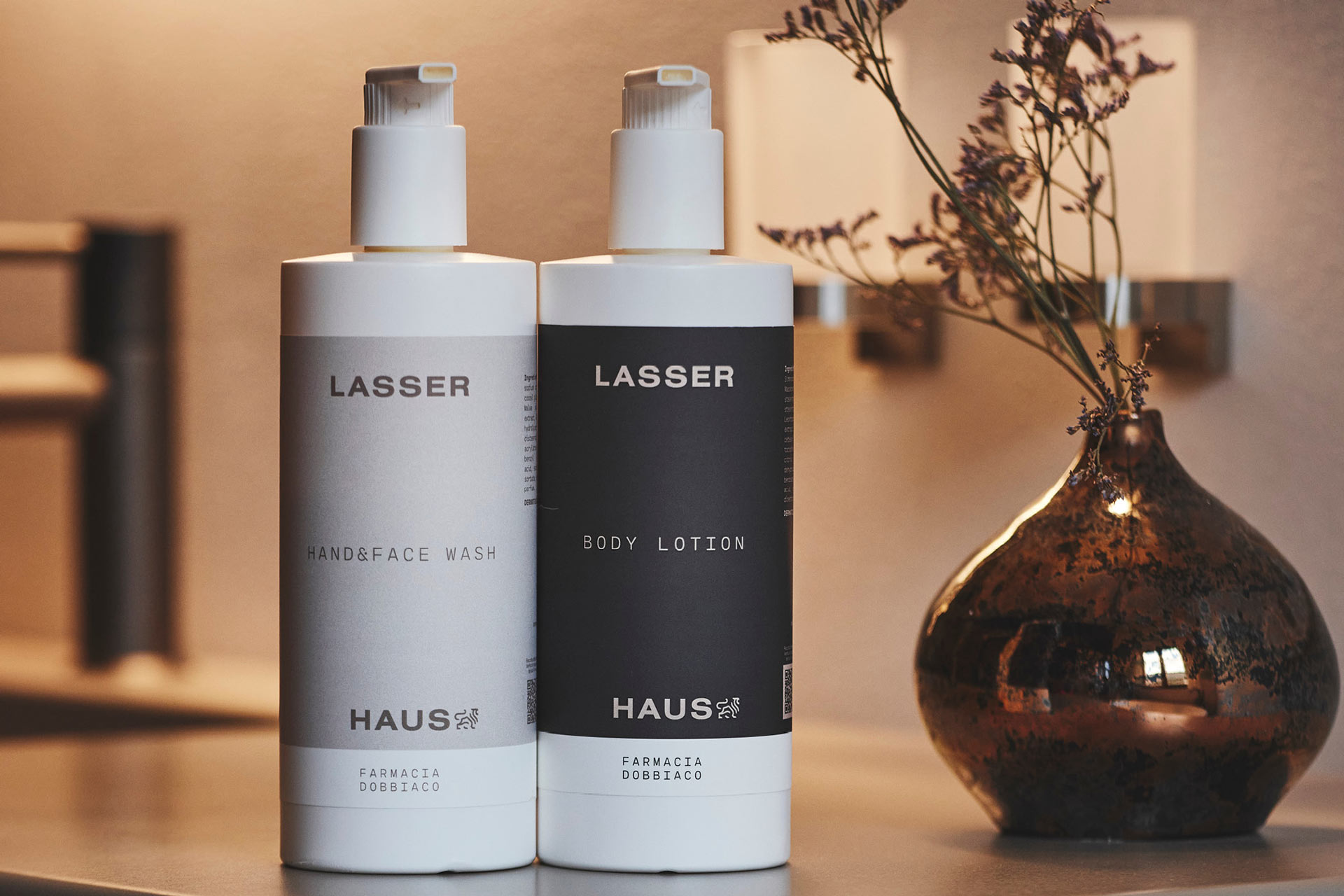 Zwei Lasserhaus Pflegeprodukte auf Ablage, flankiert von dekorativer Vase. Auf den Produkten findet sich zudem das Logo von Farmacia Dobiacco.