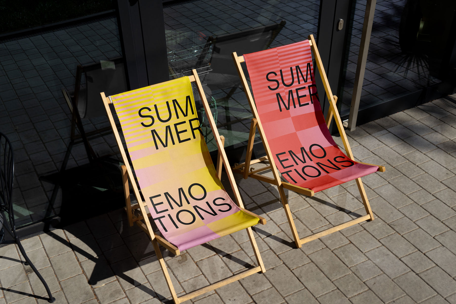 Zwei Deckstühle mit Aufschrift 'Summer Emotions' auf gepflastertem Boden.
