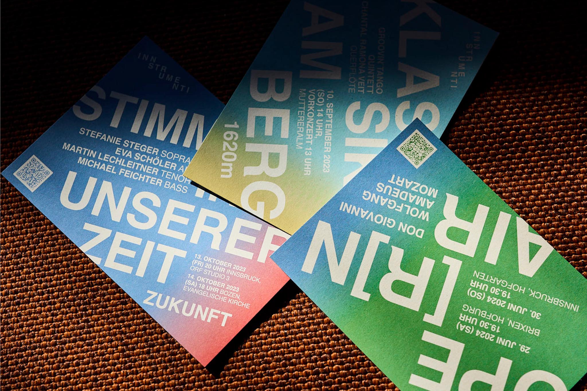Drei bunte Konzertflyer auf strukturierter Oberfläche ausgebreitet