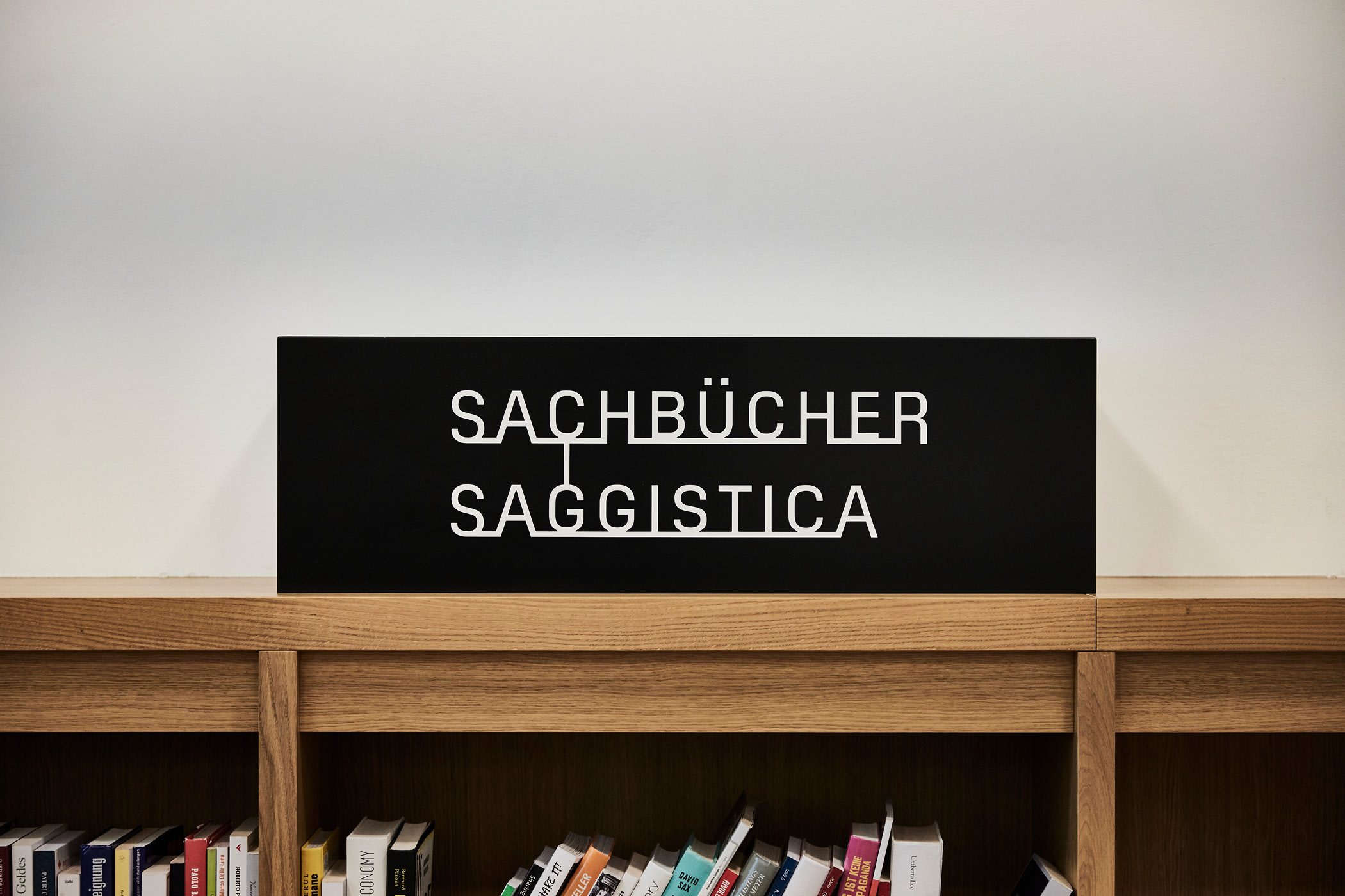 Bibliotheksschild mit Aufschrift Sachbücher Saggistica, Holzregal.