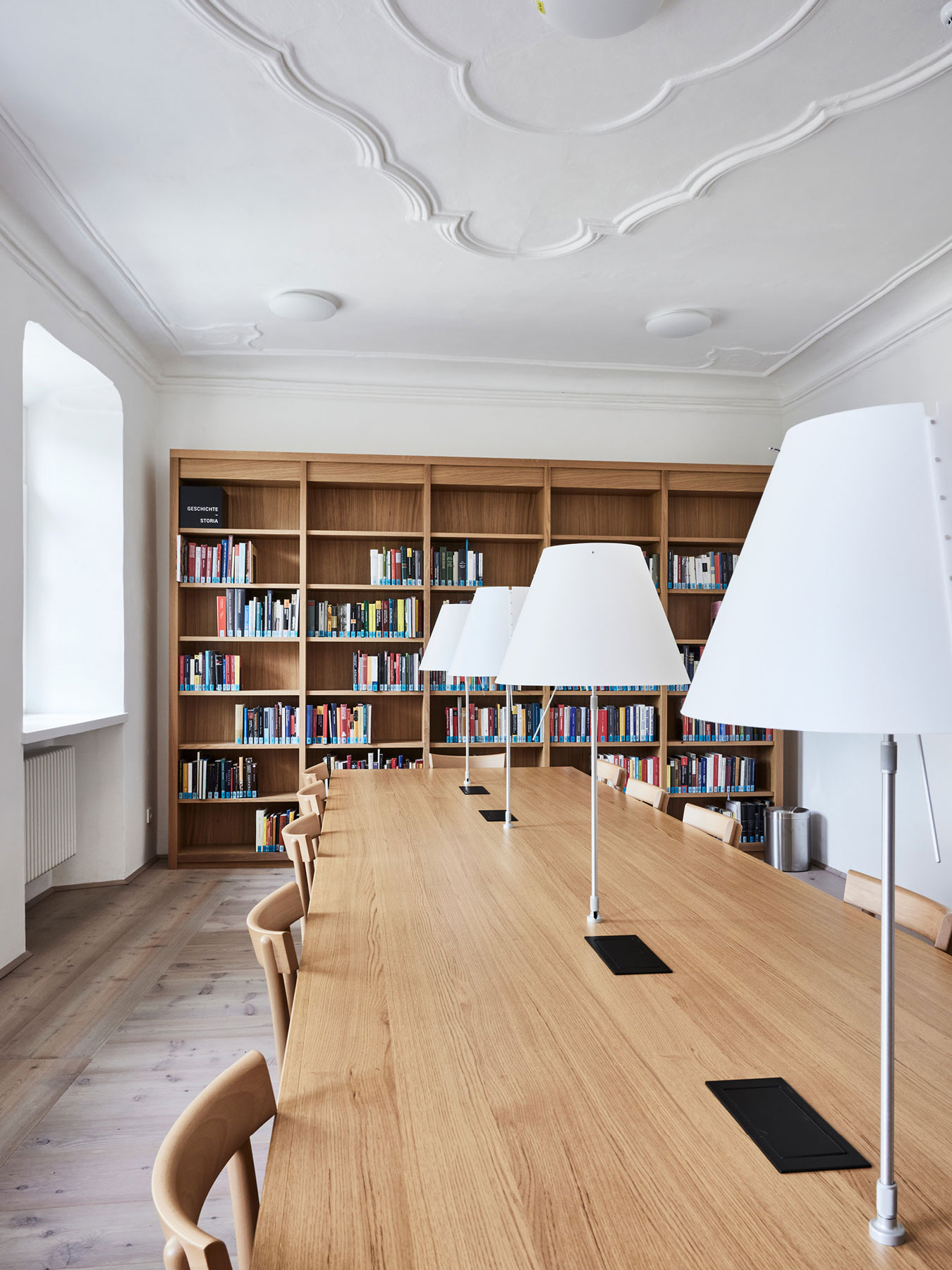 Lesesaal in moderner Stadtbibliothek mit Holztisch und Lampen