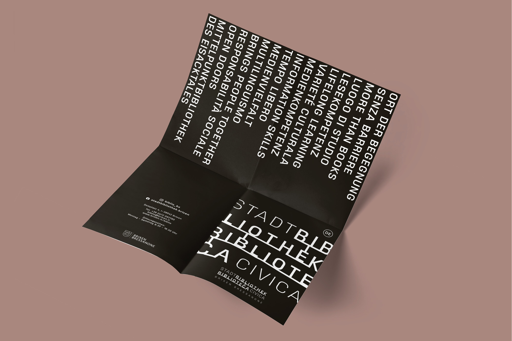 Schwarzes Faltblatt der Stadtbibliothek Brixen auf rosa Hintergrund